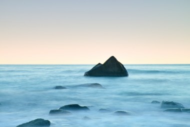 在海上的浪漫早晨。堅(jiān)持從光滑水位的巨礫。與第一個(gè)炎熱的太陽(yáng)光線的粉紅色 horozon
