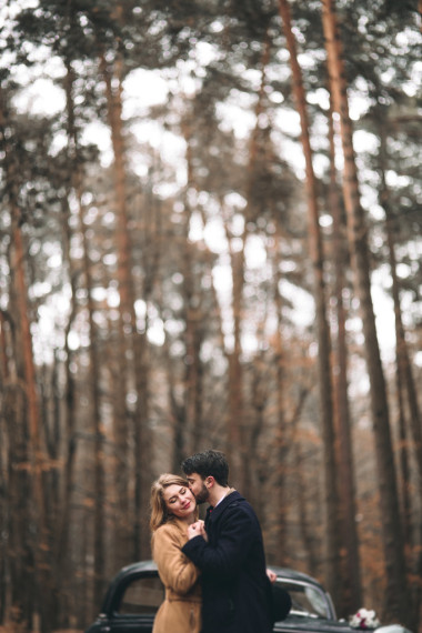 時(shí)尚愛婚禮情侶接吻和擁抱在一片松樹林附近復(fù)古車