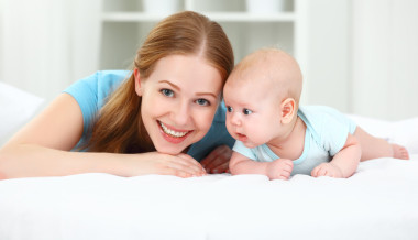 快樂(lè)家庭的母親和嬰兒在床上玩