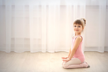 可愛的小女孩在粉紅色緊身連衣褲，坐在地板上舞蹈工作室