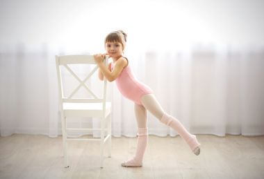 可爱的小女孩在舞蹈工作室制作新芭蕾运动椅边的粉红色紧身连衣裤