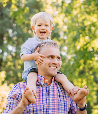 父親在他肩膀上與兒子為懷的公園里散步