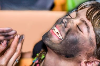 在 maskenball 的孩子脸上应用木炭的女人