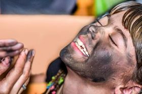 在 maskenball 的孩子脸上应用木炭的女人