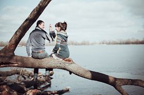 浪漫的情侣坐在树枝上附近的水