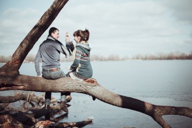 浪漫的情侣坐在树枝上附近的水 浪漫的情侣坐在树枝上附近的水