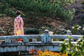一名年轻的艺妓站在京都丸山公园的桥上