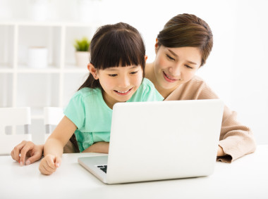 快樂的小女孩，用她的母親看著筆記本電腦