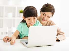 快乐的小女孩，用她的母亲看着笔记本电脑