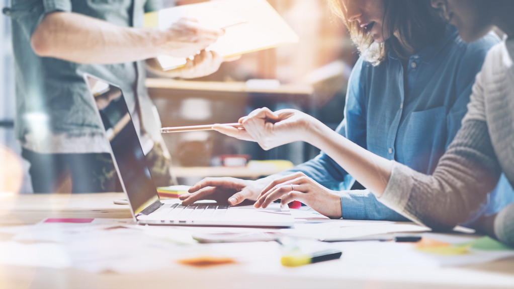 团队头脑风暴。照片年轻的创意经理团队与现代办公室的新启动项目工作。木桌上的现代笔记本。水平,胶片效果 团队头脑风暴。照片年轻的创意经理团队与现代办公室的新启动项目工作。木桌上的现代笔记本。水平,胶片效果