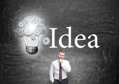 商人手到下巴在黑板前，燈泡與齒輪涂在左邊