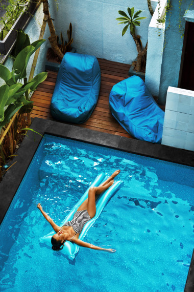 夏天的假期日光浴的女人漂浮在游泳池的水