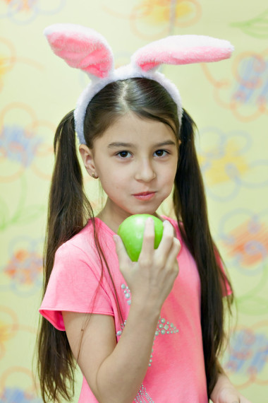 带着兔耳朵的小女孩吃了一个大的青苹果