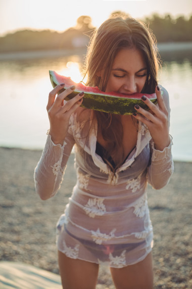 在沙灘上吃西瓜的女孩