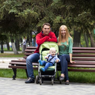 年轻的父母坐在一张长椅上，他年轻的儿子