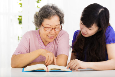 幸福的高級女人和女兒讀一本書 