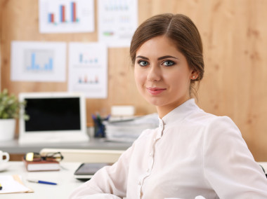 美丽微笑的商业女性坐在办公室的工作场