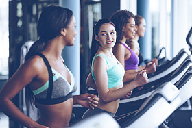 年轻漂亮的女人在跑步机上跑步