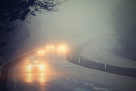 在雾中的汽车。恶劣的冬季天气和危险的汽车交通的道路上。轻型车辆在雾中