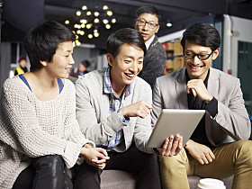年轻的亚洲商界人士在办公室使用平板电脑