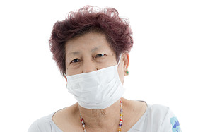 亚洲高级妇女参与保护医疗面罩上白色