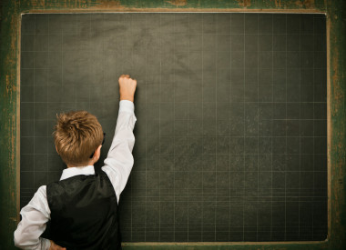 年輕的書呆子學(xué)生戴著眼鏡，黑板