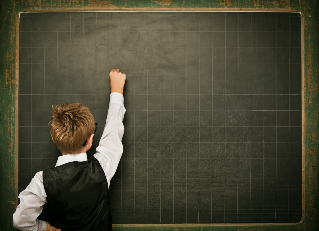 年轻的书呆子学生戴着眼镜，黑板