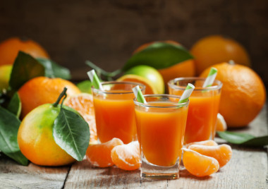 新鮮的熟桔子汁裝在小玻璃杯里有條紋吸管