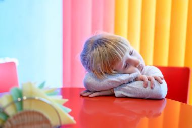 累了的小女孩，她的头在桌子上