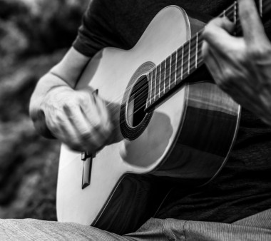 帥氣的微笑吉他手玩音樂(lè)選址上海灘巖。黑色白色戶外寫真