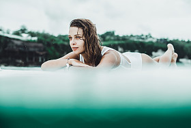 美丽的女孩在海洋冲浪在雨中