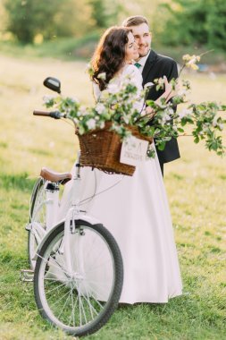 幸福的新婚夫婦在婚禮后在公園里用自行車擺弄著婚紗