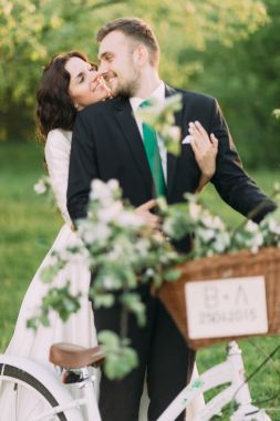 浪漫的年輕夫婦，在陽(yáng)光明媚的公園與裝飾自行車(chē)擺姿勢(shì)