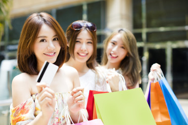 快樂的年輕女人，顯示購物袋和信用卡