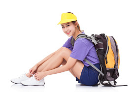 女性旅行者坐在地板上，在白色背景上，背包