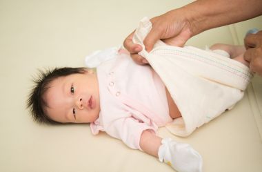 大媽媽手穿換新不是速溶的尿布的嬰兒