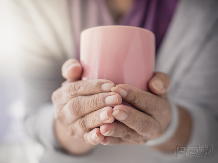 老太太拿著杯熱咖啡的飲料，在她的手