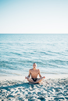 男人做瑜伽在海滩