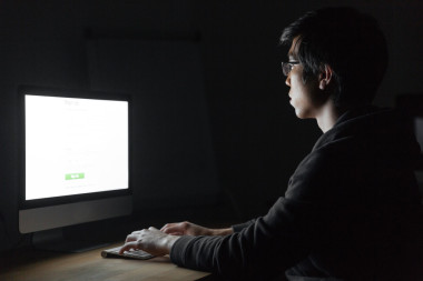 人坐在黑暗的辦公室電腦前工作時