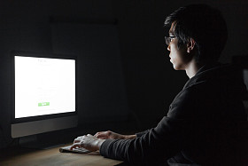 人坐在黑暗的办公室电脑前工作时