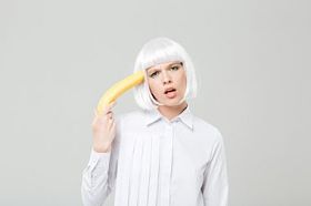 俏皮年轻漂亮的女人，在她的太阳穴附近举行香蕉