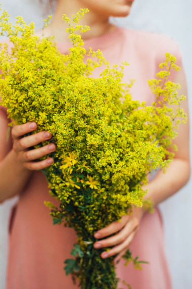 一个年轻的女人穿着玫瑰色的连衣裙手里拿着一束五颜六色的摘下来的w