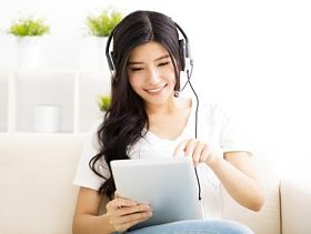 耳机和平板电脑在客厅里的年轻女子