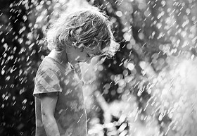 快乐的小女孩站在夏天的雨下的照片。黑色和白色