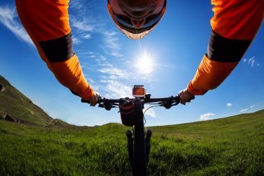 手中拿著的一輛自行車的車把的橙色夾克