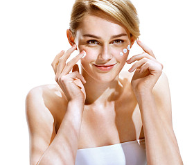 在她漂亮的脸上应用精华霜的年轻女人肖像