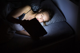 年轻女子深夜在她床上使用她的平板电脑