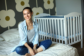 年轻女子坐在附近儿童床床上