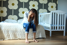 年轻疲惫的女子，坐在附近儿童床床上