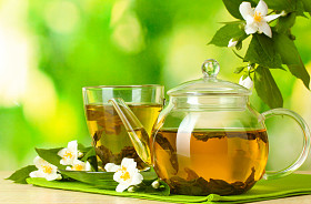 绿茶与茉莉花在杯子和绿色背景上的木桌上的茶壶